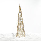 Christmas Wishes gold cone tree LED décor with an open woven design and warm white lights, displayed in a snowy setting.
