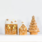 Gingerbread-style ceramic LED Christmas houses and coordinating Christmas tree displayed together, featuring white icing details and warm glowing lights.