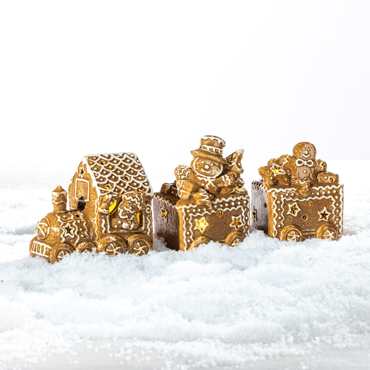 Gingerbread-style ceramic LED Christmas train with festive character-filled carriages, displayed in a snowy setting.