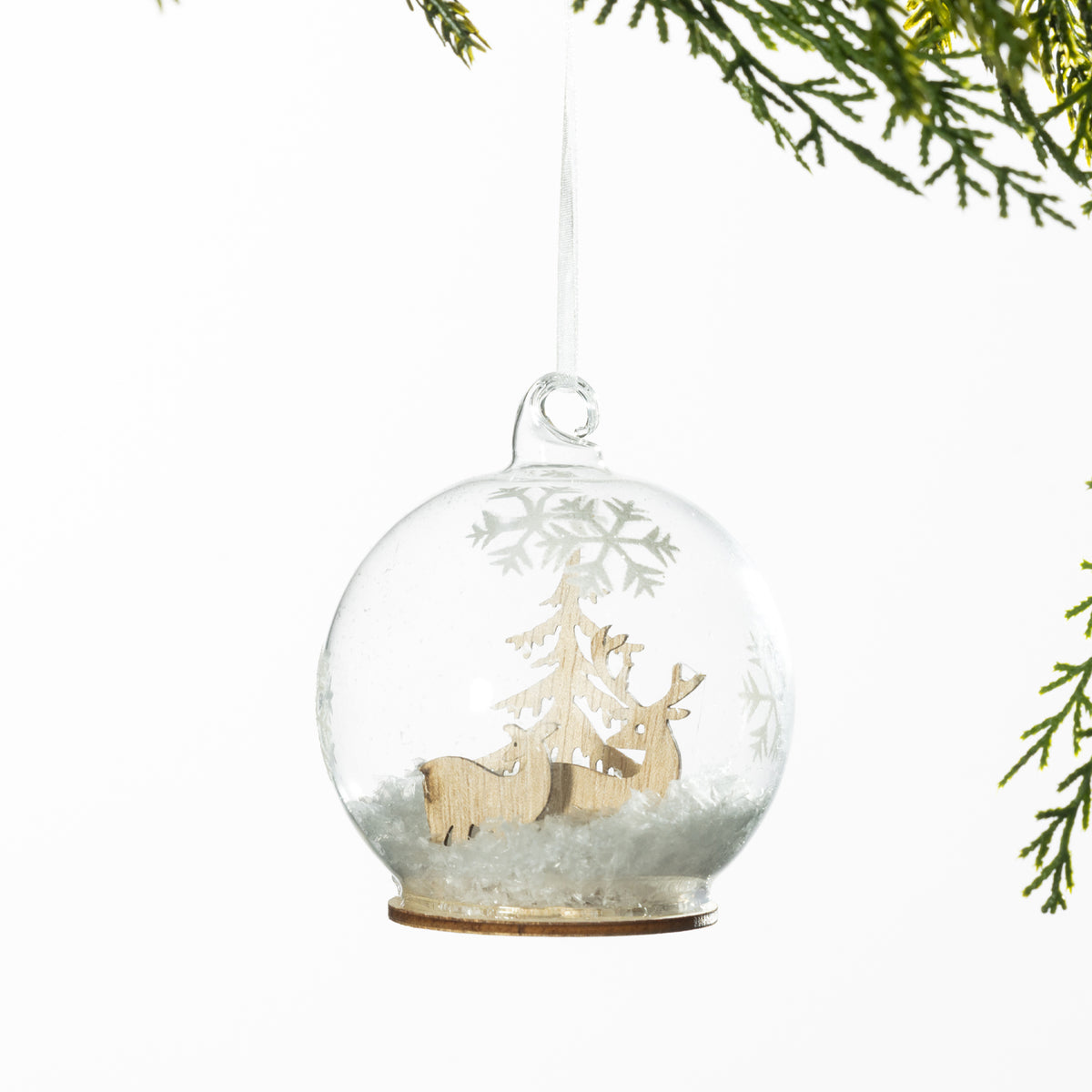 Christmas Wishes Wooden Reindeer Snow Globe Bauble – Clear snow globe-style bauble featuring a natural wooden reindeer and Christmas tree scene surrounded by faux snow, finished with a white hanging ribbon.