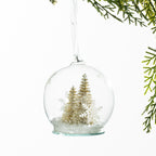 Christmas Wishes Gold Christmas Tree Snow Globe Bauble – Clear snow globe-style bauble featuring miniature gold-toned Christmas trees, snowflake accents and faux snow for an elegant winter-inspired look.