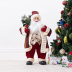 Christmas Wishes Red Traditional Santa List 80cm dressed in a red tartan and cream-trimmed outfit, holding a Christmas list and festive greenery.