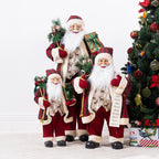Christmas Wishes traditional Santa figures in a range of sizes, dressed in coordinating red tartan and cream outfits beside a decorated Christmas tree.