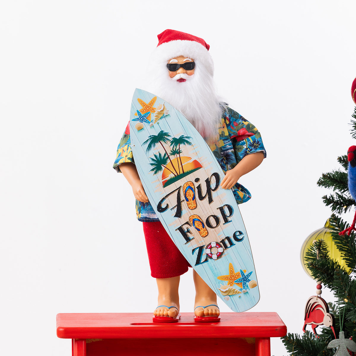 Christmas Wishes Summer Santa Surfboard 45cm wearing a tropical shirt, red shorts, sunglasses and jandals while holding a colourful surfboard.