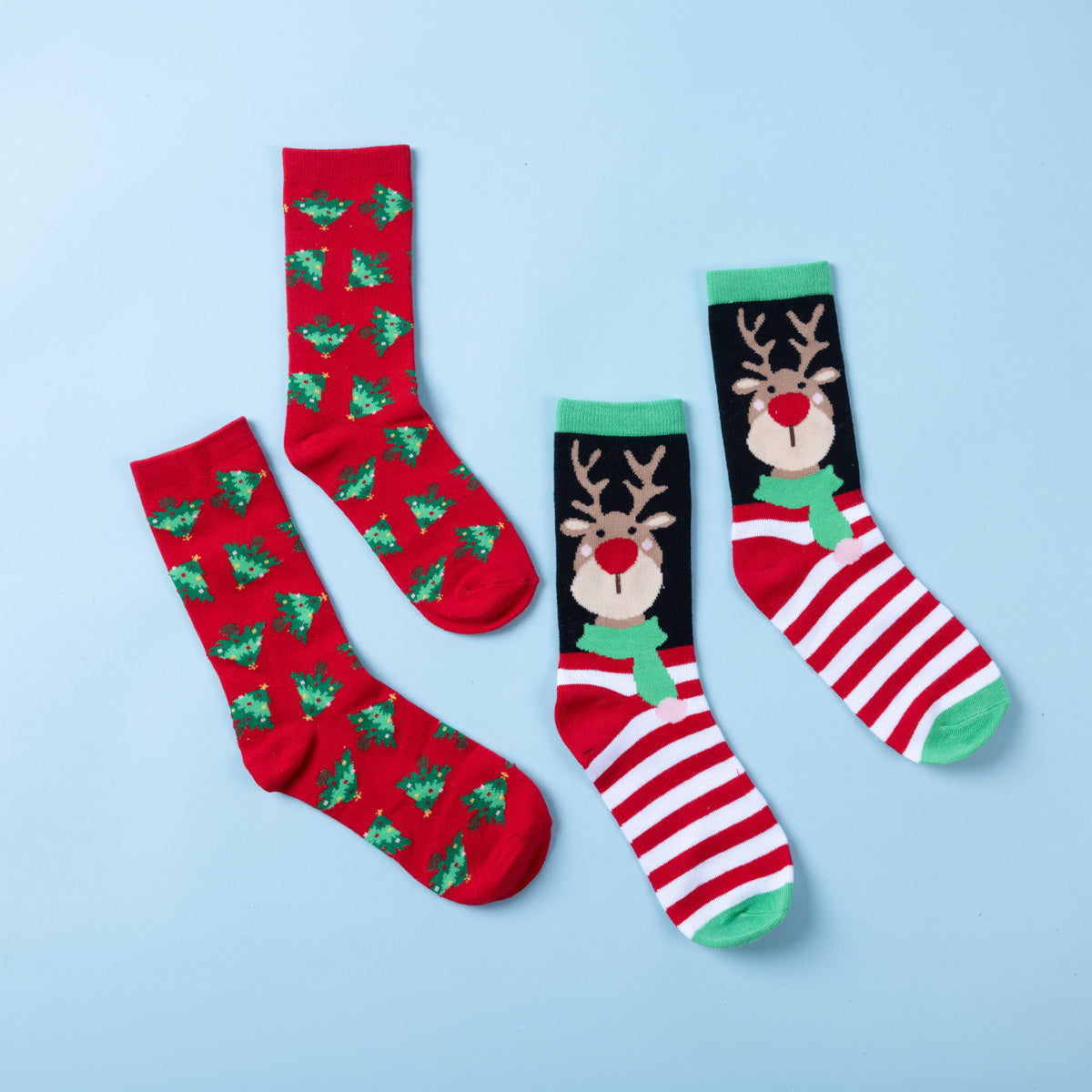 Two pairs of Christmas socks featuring red Christmas tree prints and a reindeer design with red and white stripes and green accents, displayed on a light blue background.