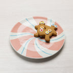 Pink and white peppermint swirl Christmas plate styled with two gingerbread cookies.