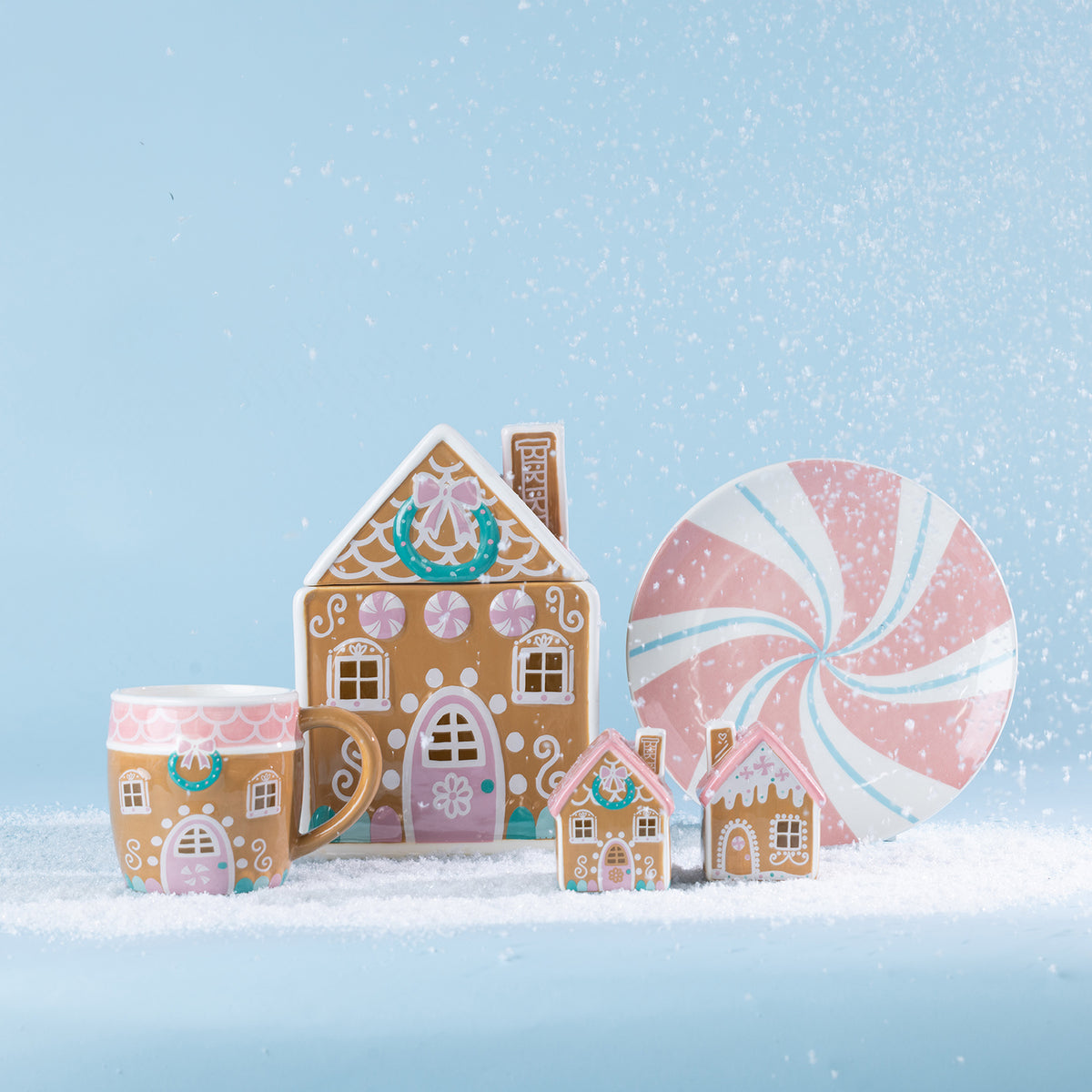 Christmas Wishes gingerbread collection displayed on a snowy blue backdrop, featuring a gingerbread house mug, candy house cookie jar, peppermint plate and decorative houses.