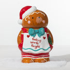 Gingerbread boy cookie jar featuring a Santa hat, teal bow and white apron with “Baking Spirits Bright” detailing.