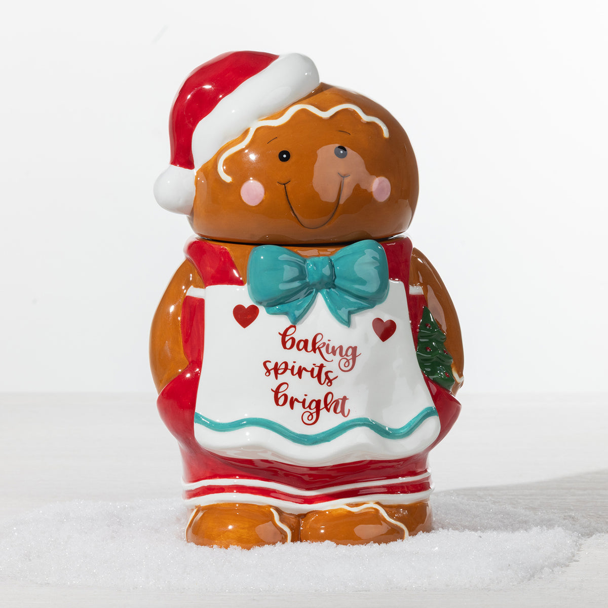 Gingerbread boy cookie jar featuring a Santa hat, teal bow and white apron with “Baking Spirits Bright” detailing.
