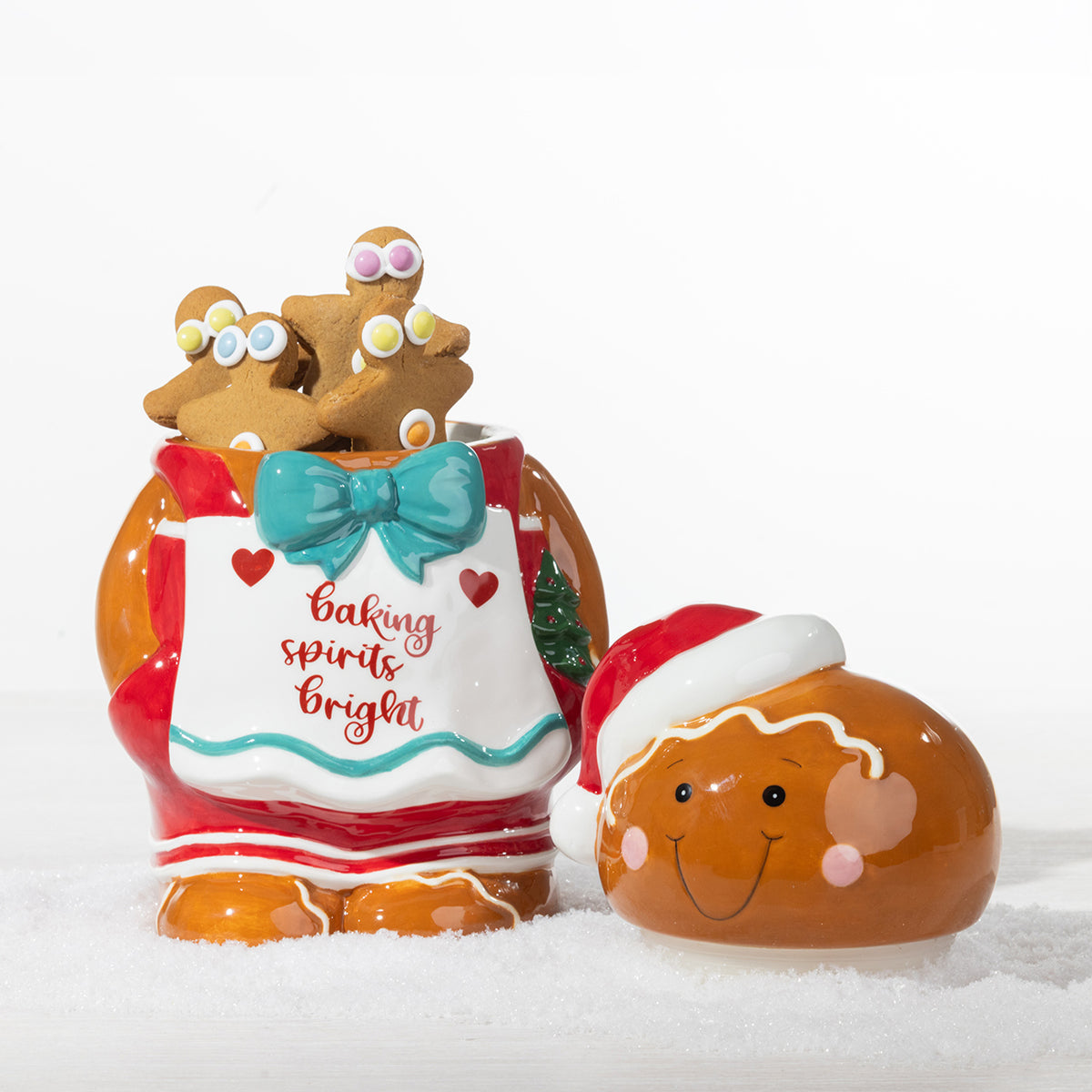 Gingerbread boy cookie jar shown open and filled with gingerbread cookies, featuring a festive apron, teal bow and Santa hat.