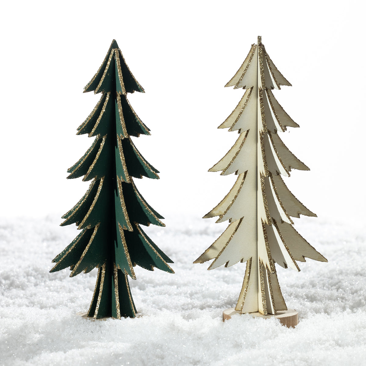 Two decorative miniature Christmas trees standing in white faux snow. One tree is dark green with gold glitter edges, and the other is light beige with gold glitter edges.