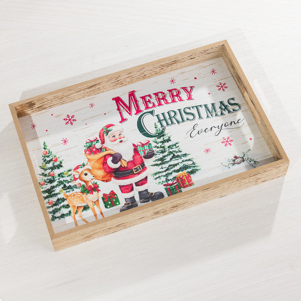 A rectangular wooden serving tray with a clear glass top, featuring a festive Christmas illustration of Santa Claus, a reindeer, Christmas trees, and the words 'Merry Christmas Everyone' on a white wood-plank style background.