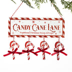 A festive Christmas hanging sign that reads 'CANDY CANE LANE' with 'Traditional Christmas Sweets & Treats' underneath. The sign has a red-and-white striped border and hangs from red-and-white string, with four candy cane ornaments dangling below, each tied with a red ribbon.