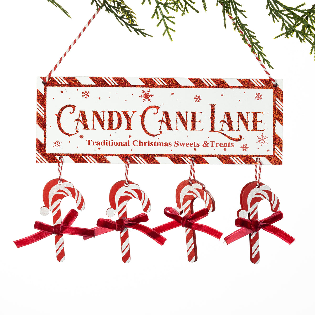 A festive Christmas hanging sign that reads 'CANDY CANE LANE' with 'Traditional Christmas Sweets & Treats' underneath. The sign has a red-and-white striped border and hangs from red-and-white string, with four candy cane ornaments dangling below, each tied with a red ribbon.