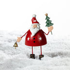 Christmas Wishes Metal Standing Santa Décor Red – Festive metal Santa figure in red holding a miniature Christmas tree and gold bell, displayed in a snowy setting.