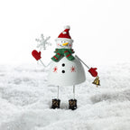 Christmas Wishes Metal Standing Snowman Décor White – Cheerful white metal snowman figure wearing a red Santa hat and green scarf, holding a snowflake and gold bell.