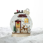 Christmas Wishes Wooden Merry Christmas Bauble LED Décor – Wooden bauble-shaped Christmas decoration featuring a festive front door scene with reindeer, miniature trees, “Merry Christmas” lettering and warm LED lighting.