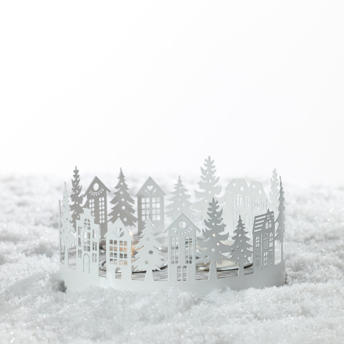 Christmas Wishes Metal Village Candle Holder – White metal village-style tealight holder featuring layered cut-out houses, trees and festive woodland details.