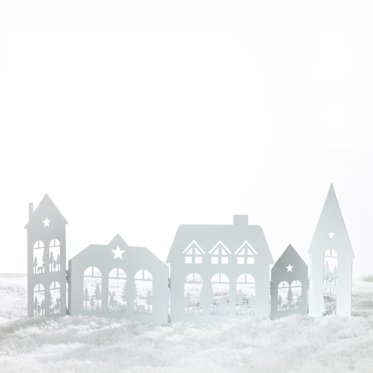 Christmas Wishes Metal Village Screen – White metal folding Christmas village screen featuring cut-out houses, windows, stars, trees and reindeer scenes.