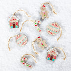 A set of eight Christmas ornaments made from natural wood, featuring gingerbread men, gingerbread houses, candy canes, and patterned baubles, each hanging from a jute twine loop on a white textured background.