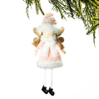 A hanging Christmas angel ornament with a pink and white fluffy dress, gold wings, and black shoes, shown against a white background with pine branches at the top.