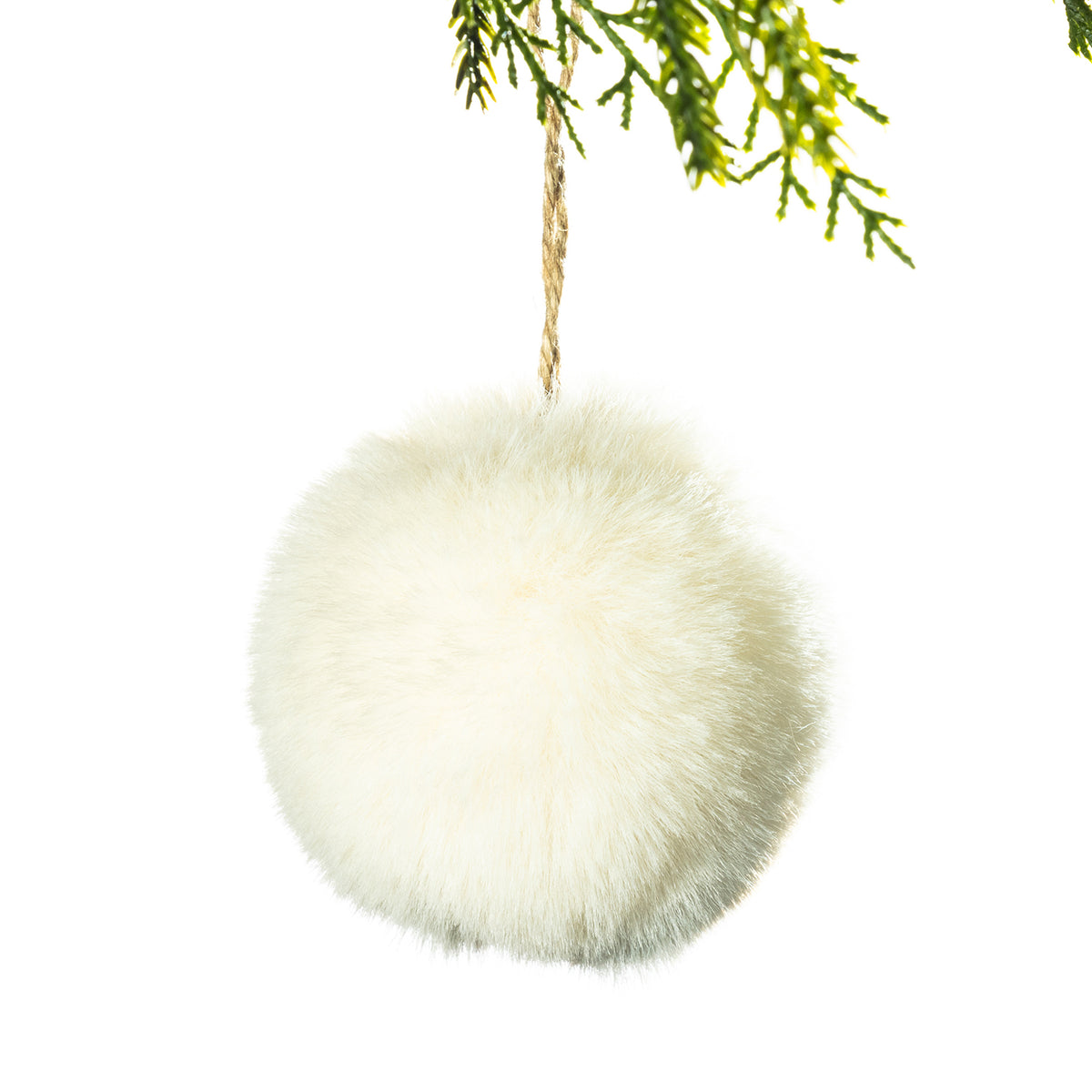 A fluffy cream faux-fur hanging ornament or pom-pom decoration suspended by a natural jute string from green pine branches, isolated on a white background.
