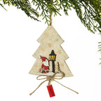 A Christmas tree-shaped hanging ornament made from textured cream paper with a small Santa and street lamp illustration, tied with twine and a red 'XMAS' tag, shown hanging from green pine branches against a white background.