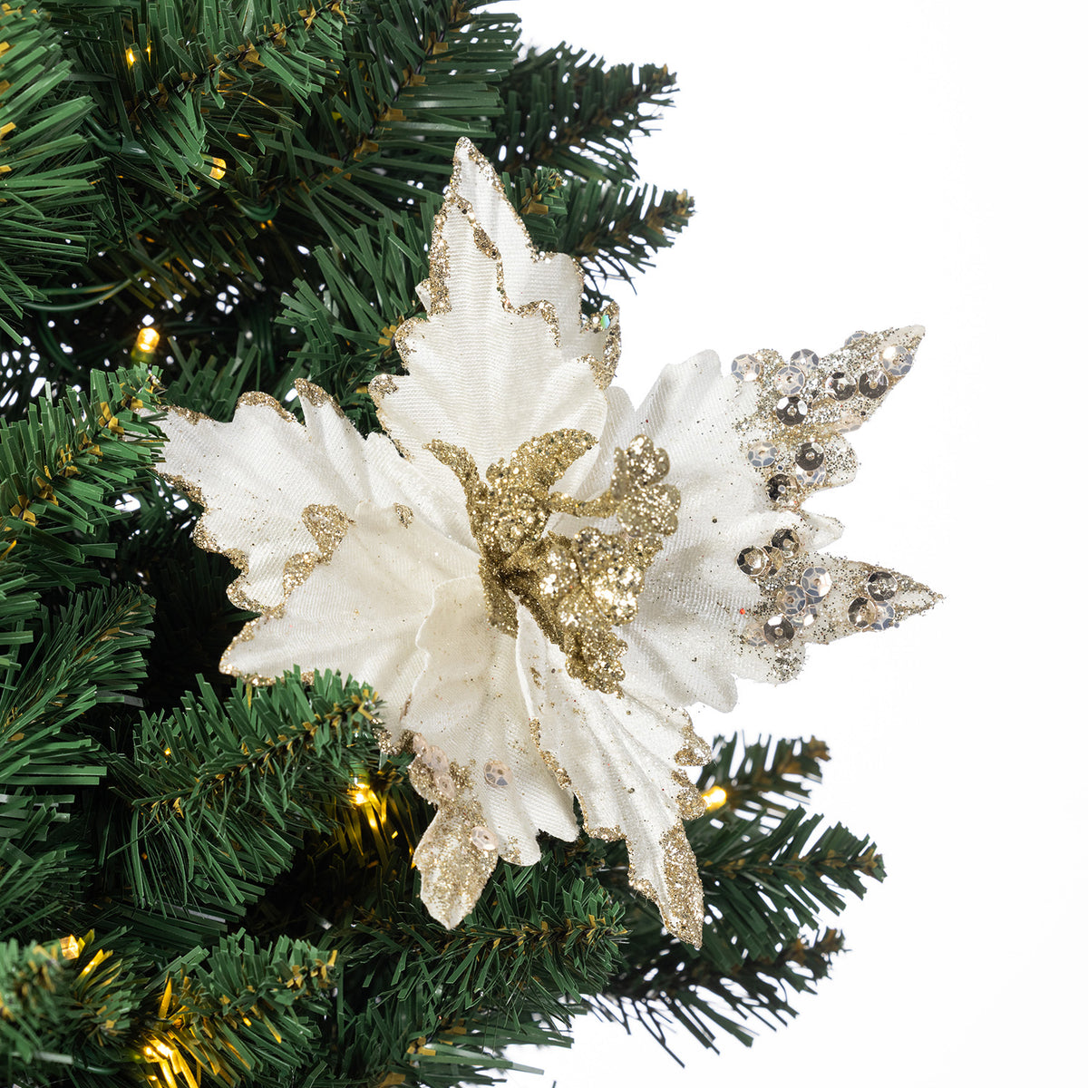 A white artificial poinsettia-style Christmas ornament with glittery gold accents and rhinestone-embellished wings, displayed on a green Christmas tree branch against a white background.