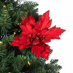 A bright red artificial poinsettia flower ornament with glittery edges, displayed on a green artificial Christmas tree branch against a white background.