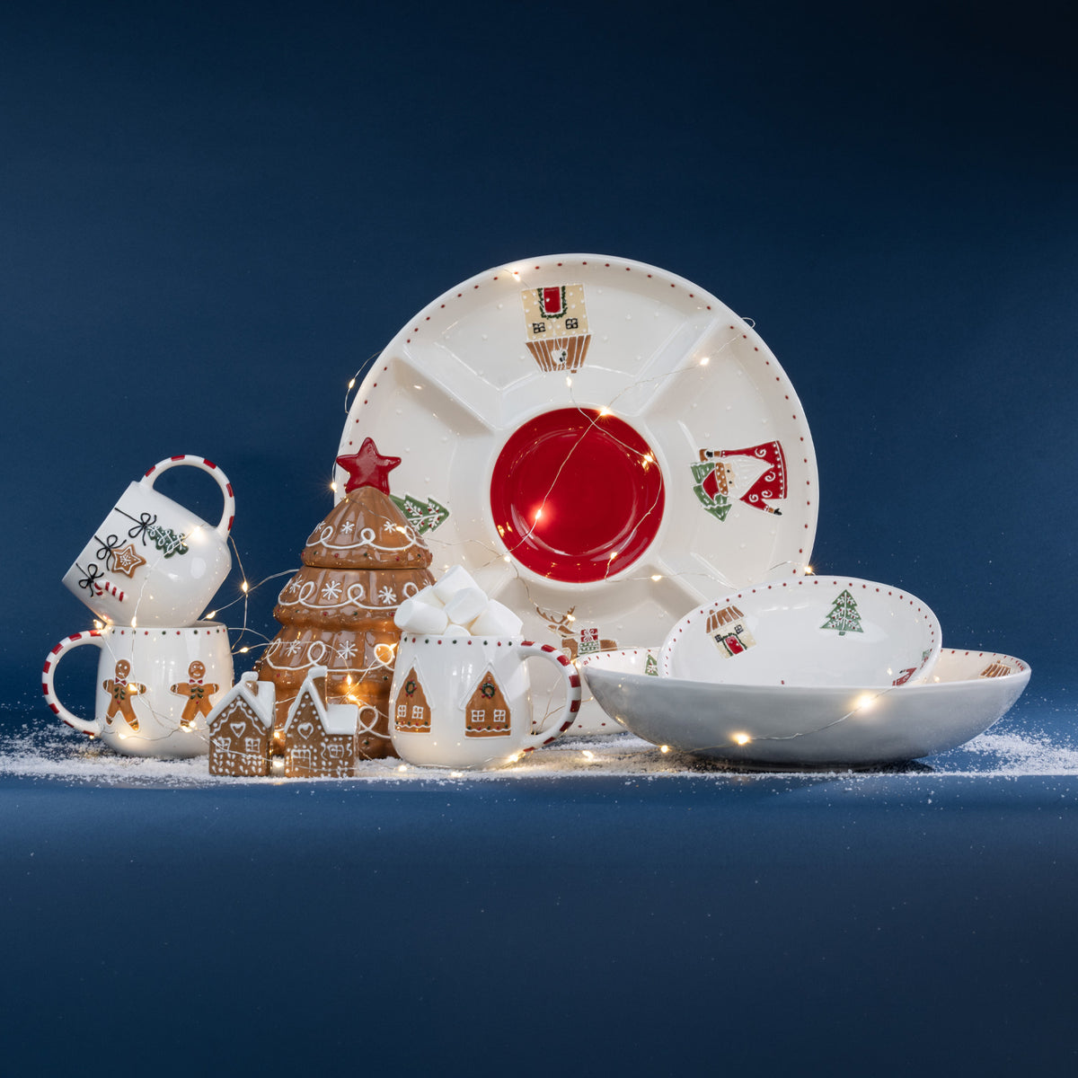 A festive Christmas tableware collection featuring playful gingerbread designs, twinkling fairy lights and snowy accents against a rich navy backdrop.