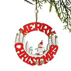 A circular wooden Christmas ornament hanging from a tree branch, featuring red 'MERRY CHRISTMAS' lettering, a white snowman, white trees, and small gold star accents on a white background.