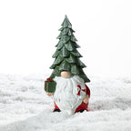 Christmas Wishes Shy Gnome Tree Hat with Present Décor – Festive gnome decoration wearing a tall green Christmas tree hat, with a long white beard, red outfit, green present and candy cane.