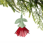 A red felt pōhutukawa flower Christmas decoration featuring a sage green leaf and stem design with long red fringed petals, hanging from a Christmas tree branch against a white background.