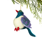 A felted nz bird ornament hanging from a pine branch against a white background. 