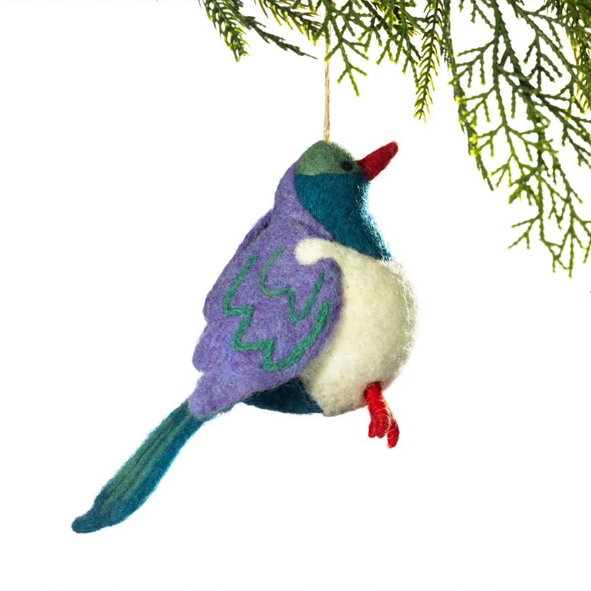A felted nz bird ornament hanging from a pine branch against a white background. 