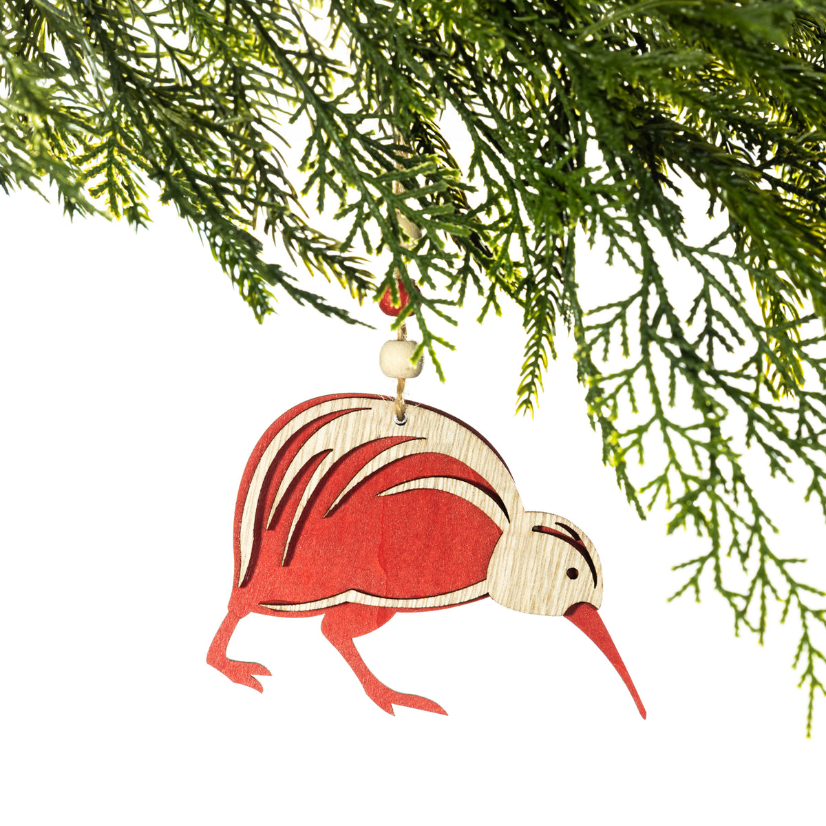 A wooden kiwi Christmas decoration featuring a red and natural wood design, layered feather detailing, a long red beak and a natural hanging cord with a wooden bead, displayed on a Christmas tree branch against a white background.