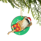 A wooden Santa Christmas decoration featuring a fluffy white beard, black sunglasses, red floral board shorts and a Santa hat, relaxing on a green polka dot pool float, hanging from a Christmas tree branch against a white background.