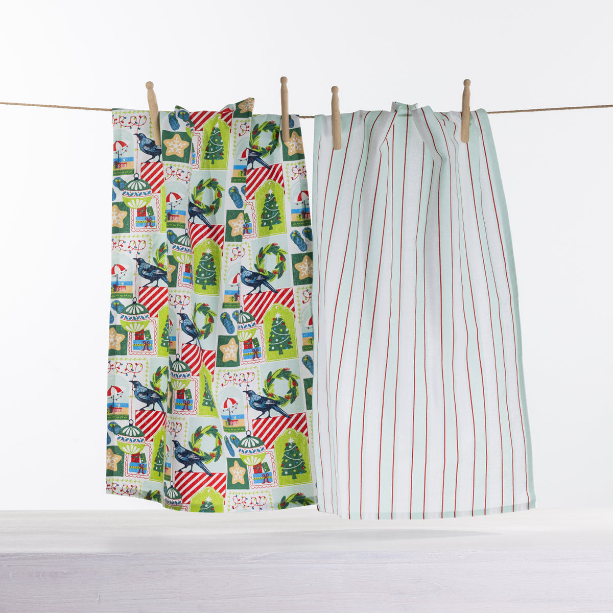 Christmas Wishes Kiwi Christmas tea towel 2 pack with colourful festive New Zealand-inspired print and pale blue striped tea towel hanging on a line.