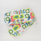 Christmas Wishes Kiwi Christmas double oven glove featuring a colourful patchwork-style print with Christmas trees, native birds, wreaths, ornaments and gifts.