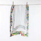 Christmas Wishes Kiwi Christmas Food Cover hanging on a line, showing the white mesh construction with colourful printed fabric edging.