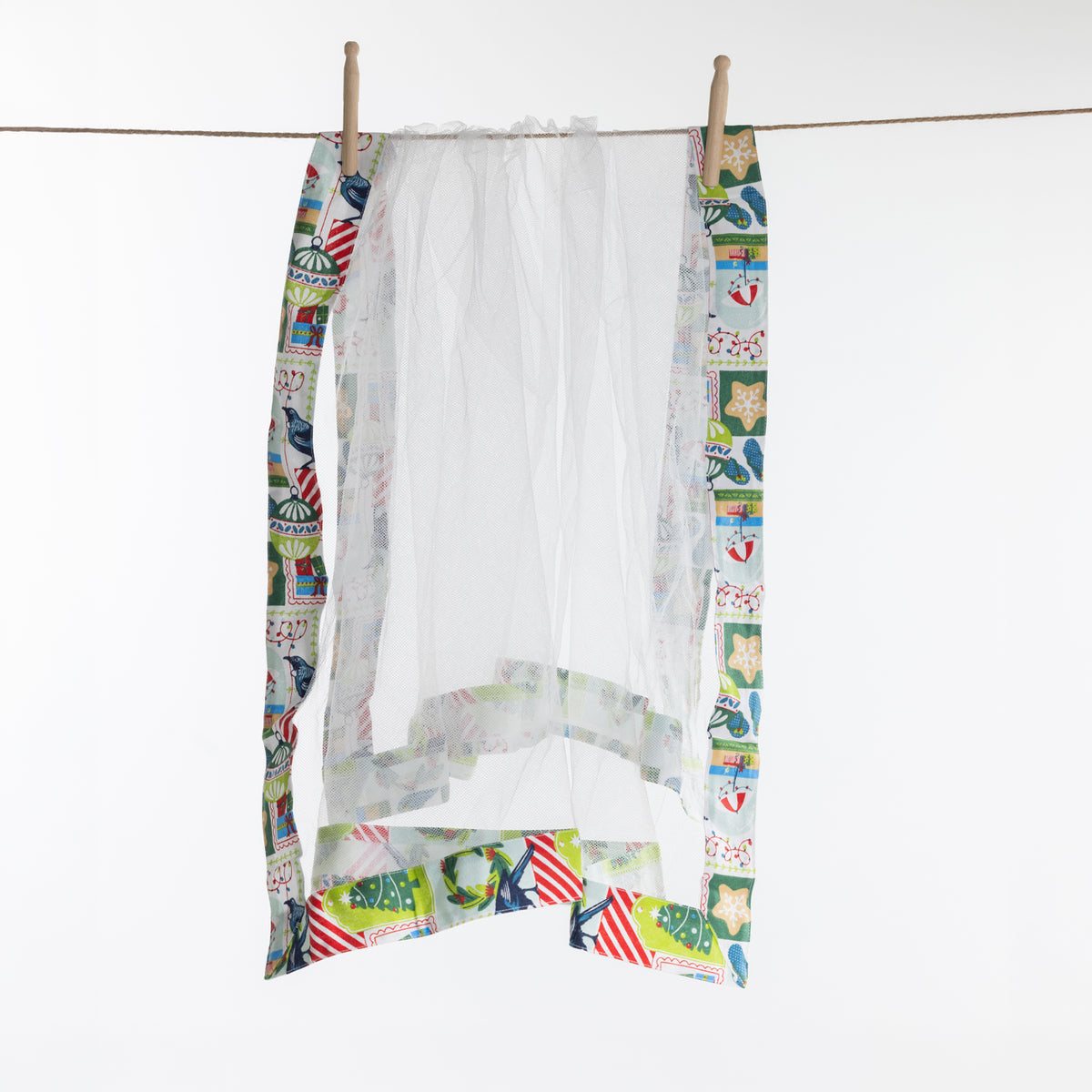 Christmas Wishes Kiwi Christmas Food Cover hanging on a line, showing the white mesh construction with colourful printed fabric edging.