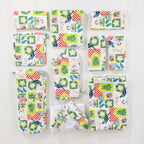 Christmas Wishes Kiwi Christmas kitchen collection arranged flat, featuring coordinating oven gloves, pot holders, napkins, food cover and other festive accessories.