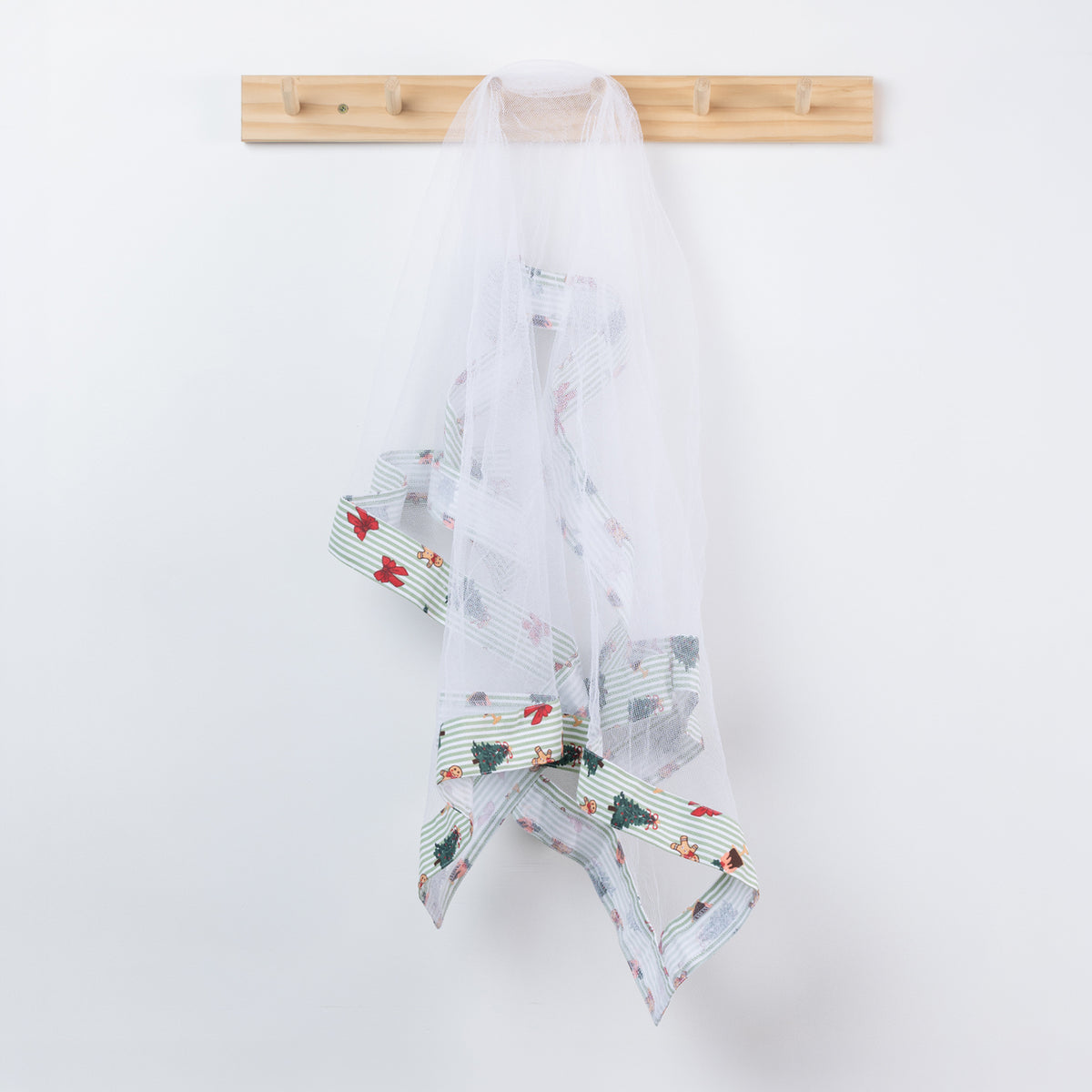 Christmas Wishes Classic Christmas Food Cover hanging from a wooden hook, featuring white mesh with green striped trim and festive Christmas motifs.