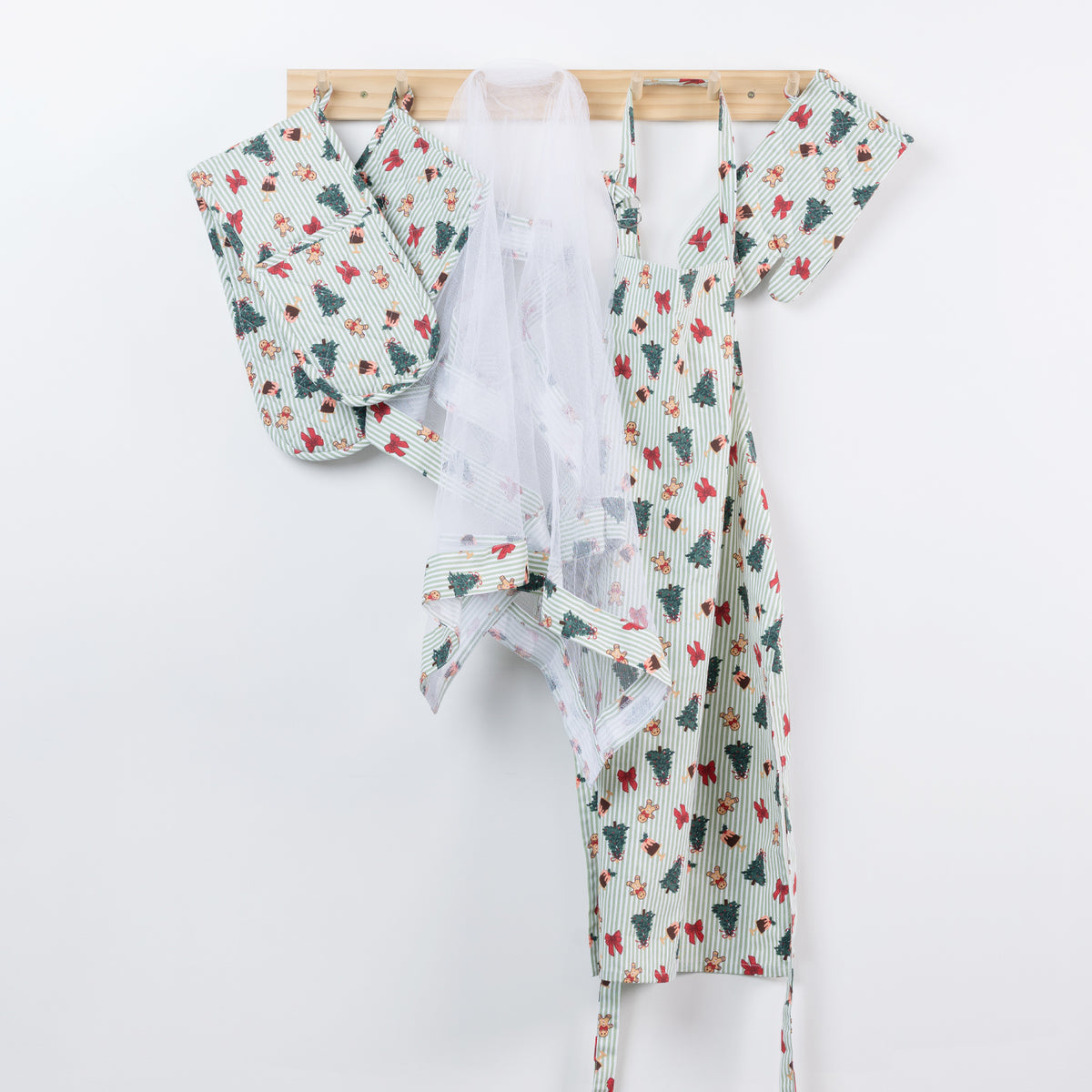 Christmas Wishes Classic Christmas kitchen range hanging from wooden hooks, including the food cover, apron and coordinating oven gloves in the festive green print.