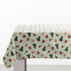 Christmas Wishes Classic Christmas Tablecloth draped over a dining table, featuring green and white stripes with Christmas trees, gingerbread people, red bows and festive puddings.