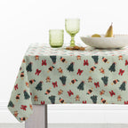 Christmas Wishes Classic Christmas Tablecloth styled on a dining table with green glassware, a white serving bowl and festive gingerbread decorations.