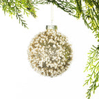 Champagne round Christmas bauble decorated with sparkling gold glitter and clear beaded detailing, hanging from festive greenery.