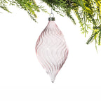 Pink elongated glass Christmas bauble featuring delicate swirling ribbed detailing and a pointed teardrop shape, hanging from festive greenery.