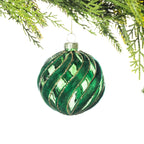 Green glass Christmas bauble featuring a swirling velvet design with gold glitter detailing, hanging from festive greenery against a white background.