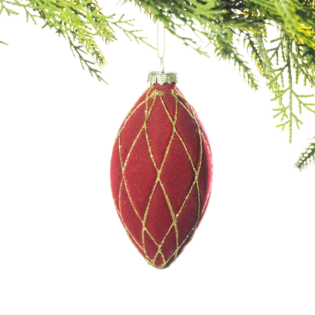 A long red velvet Christmas bauble with a gold glitter diamond lattice pattern hanging from festive greenery against a white background.